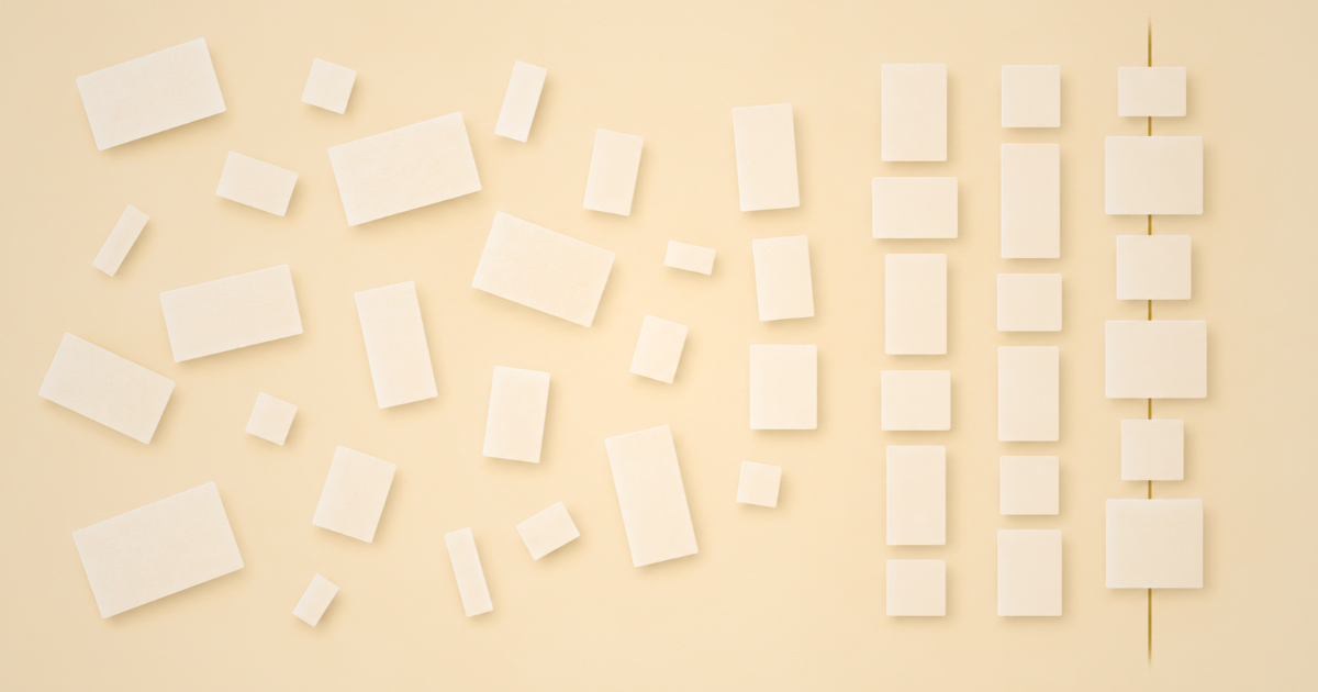 A grid of paper cards in rows and columns with one gold line joining matching cells down a column, showing how a literature review matrix reveals patterns